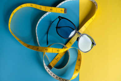 蓝色背景下黄色太阳镜和皮尺静物图