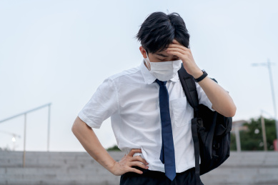 亚洲男生戴着口罩低头扶额