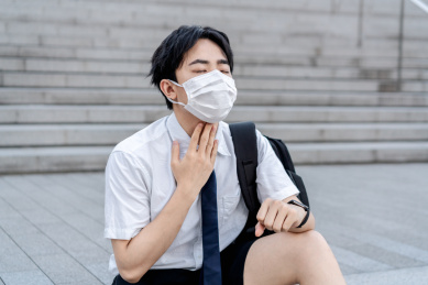 年轻亚洲男生戴着口罩喉咙疼