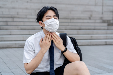 年轻亚洲男生戴着口罩喉咙疼