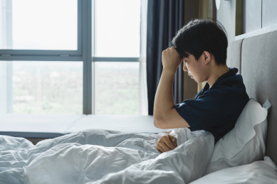 亚洲生病男子在床上摸额头