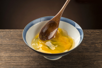 使用木勺打鸡蛋勺盛鸡蛋液特写木桌面背景