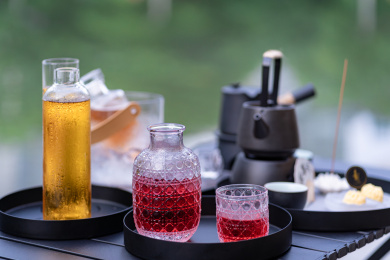 湖边木桌上摆放的酒具茶具果酒