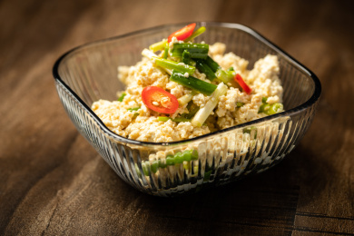 棕色木纹桌面上放着一盘小葱拌豆腐