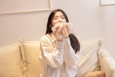 一位美女坐着沙发上捂着口鼻打喷嚏