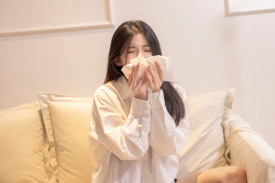 一位美女坐着沙发上捂着口鼻打喷嚏