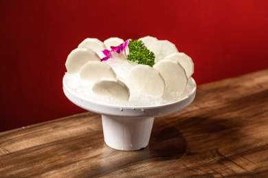 棕色木纹桌上放着一盘白萝卜片