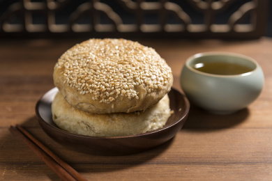 传统面食芝麻烧饼特写木桌面古窗棂背景
