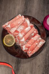 白盘子里有一份切好的羊肉卷