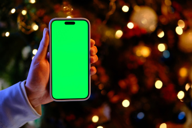 圣诞节晚上手展示绿色屏幕的智能手机