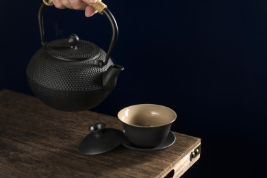 手持铁壶向盖碗中倒茶特写深色调