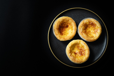 一盘美味的蛋挞放在黑色背景上