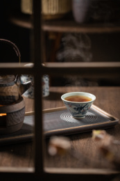 放在窗口旁木桌上的一杯热茶和茶壶