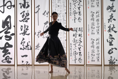 一位身穿民族服饰美女在书法前跳舞