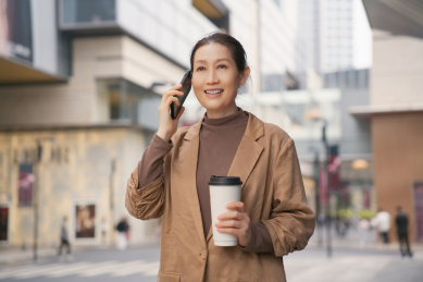 微笑的职业女性多任务处理电话和咖啡
