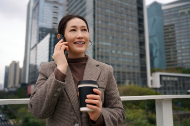 微笑的职业女性多任务处理电话和咖啡