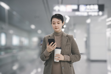 在城市地铁内使用智能手机喝咖啡的职业女性