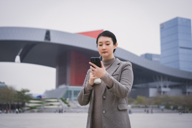 年轻的职业女性在旅途中使用智能手机和咖啡