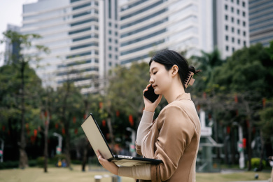 在户外使用笔记本电脑打电话的职业女性