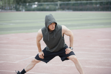 青年男子在学校操场做拉伸热身，准备打篮球