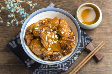 一碗红烧牛窝骨摆放在木桌面上特写