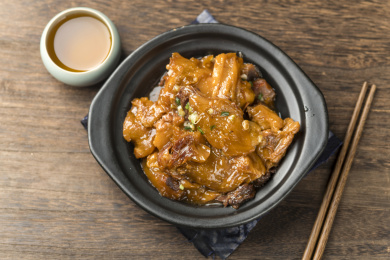 用筷子从砂锅中夹起红烧牛窝骨特写深色调