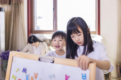 客厅里年轻的母亲陪着姐弟俩做游戏