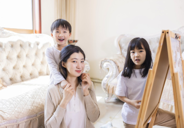 客厅里年轻的母亲陪着姐弟俩做游戏