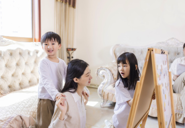 客厅里年轻的母亲陪着姐弟俩做游戏