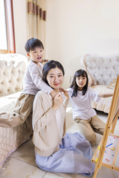 客厅里年轻的母亲陪着姐弟俩做游戏