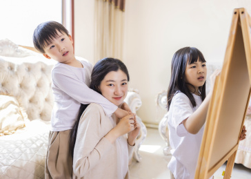 客厅里年轻的母亲陪着姐弟俩做游戏