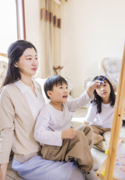 客厅里年轻的母亲陪着姐弟俩做游戏