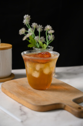 桌面上的杯子里的甘甜可口的冰木橘茶