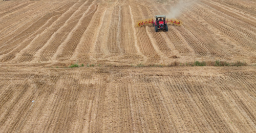 麦收季节中原乡村麦田里秸秆打包机繁忙场面