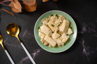 桌面上的盘子里的美味可口的小葱拌豆腐