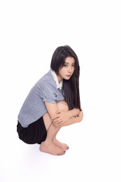 白背景前蹲在地上的年轻东方少女