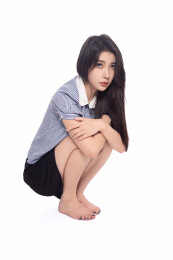 白背景前蹲在地上的年轻东方少女