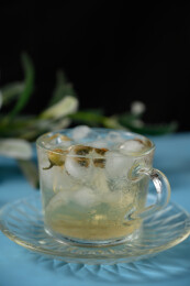 桌面上的杯子里的甘甜可口的冰茶花花茶
