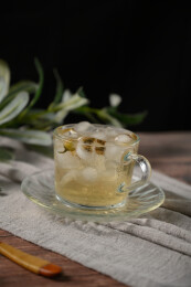 桌面上的杯子里的甘甜可口的冰茶花花茶
