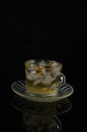 桌面上的杯子里的甘甜可口的冰茶花花茶