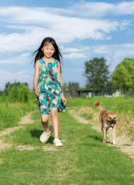 小狗跟着小女孩走在乡间田野里