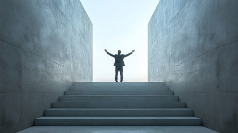 商业人士站在楼梯顶端高举手臂奋斗成功