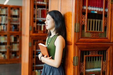 女生书架旁看书