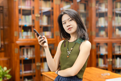 女生在图书馆使用手机