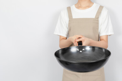 白色背景中一个年轻女人手拿铁炒锅