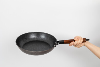 一只手拿着空的麦饭石平底锅颠锅动作