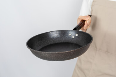 一只手拿着空的麦饭石平底锅颠锅动作