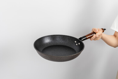 一只手拿着空的麦饭石平底锅颠锅动作