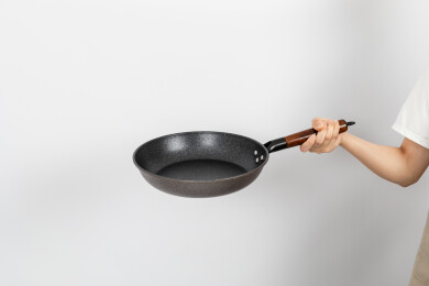 一只手拿着空的麦饭石平底锅颠锅动作