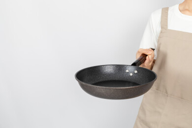 一只手拿着空的麦饭石平底锅颠锅动作